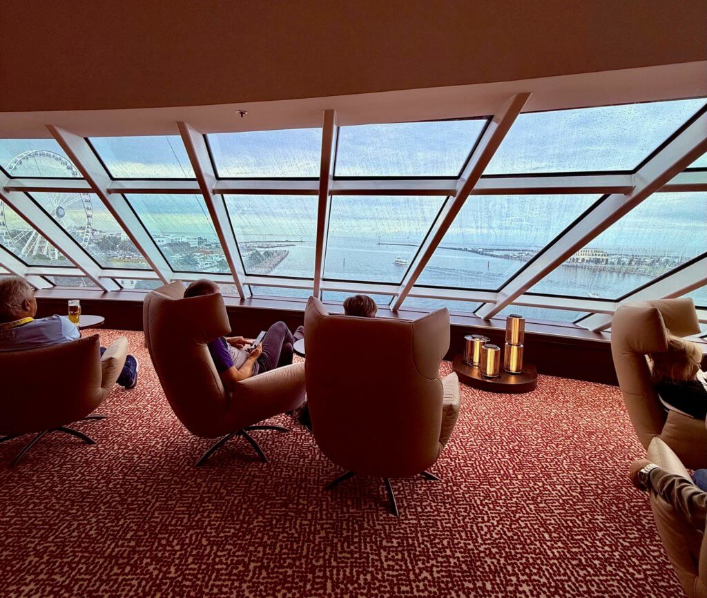 Innenansicht der Panorama Lounge & Bar auf der AIDAdiva nach der Renovierung 2025, mit großen Panoramafenstern, hellen Sesseln und Meerblick über den Bug.