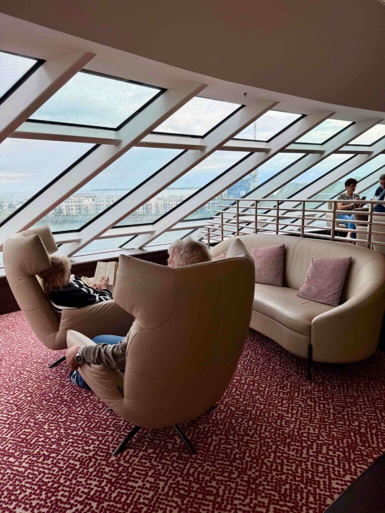 Innenansicht der Panorama Lounge & Bar auf der AIDAdiva nach der Renovierung 2025, mit großen Panoramafenstern, hellen Sesseln und Meerblick über den Bug.